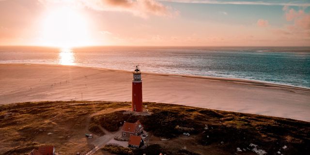Camping in Holland am Meer: Leuchtturm auf der Insel Texel vor dem Horizont mit Sonnenuntergang