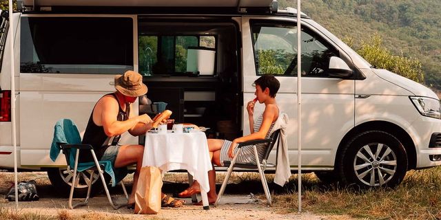Two people sitting outside in front of a CamperBoys van