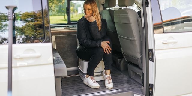 Eine Frau sitzt voll angezogen im Innern eines Campers auf einer Campingtoilette. In diesem Artikel erfährst du das Wichtigste zum Thema Chemietoilette entsorgen.