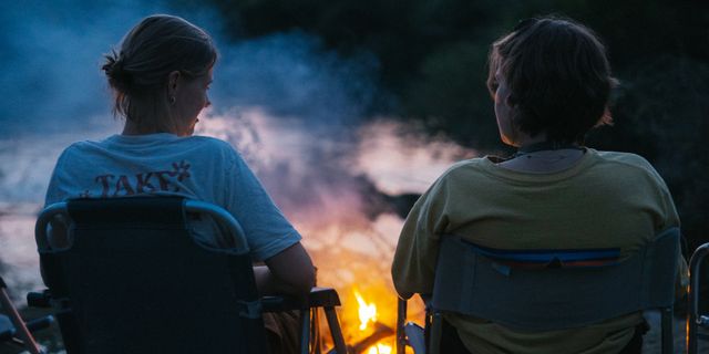 Ein Mann und eine Frau sitzen in Campingstühlen vor einem Lagerfeuer
