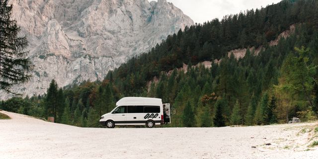 Dolomiten Geheimtipps: Ein Off Camper steht beim Dolomiten Camping vor einem Bergpanorama, während eine Frau die Hecktüre öffnet