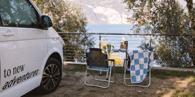 Ein gedeckter Campingtisch vor dem Gardasee in Italien neben einem Off Camper