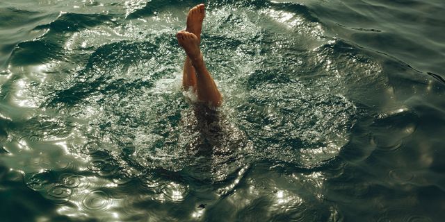 Eine Frau springt in einen See, man sieht nur noch die Füße