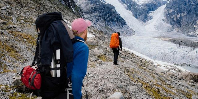 Zwei Freunde in Wanderausrüstung beim Wandern in einem norwegischen Gletscher. Norwegen Geheimtipps und Alternativen zu den beliebtesten Spots verraten wir dir hier.