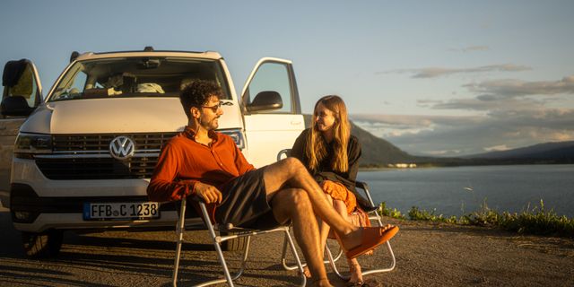 Ein Paar sitzt neben einem Camper in Norwegen.