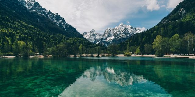 Kristallklarer Bergsee vor schneebedeckten Gipfeln