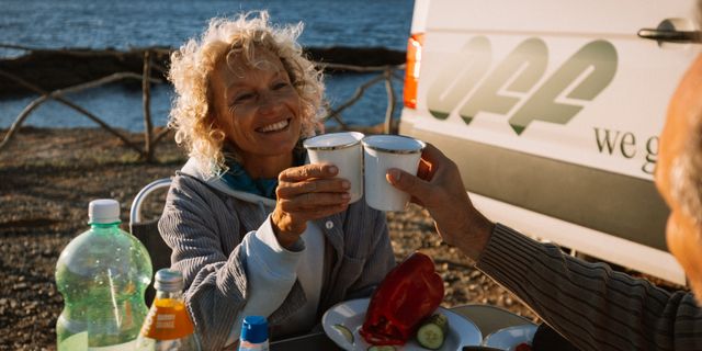 Frau sitze vor Camper am Meer