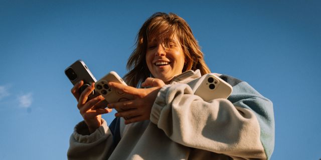 Mädchen mit multiplen Handys vor blauem Himmel Hintergrund