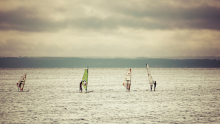 Fünf Windsurfer auf dem offenen Meer