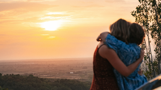 Gay Travel Index: Ein lesbisches Paar umarmt sich neben ihrem Camper während dem Sonnenuntergang.