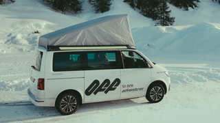 Nachteile Aufstelldach: Ein Camper mit grauer Dachzeltisolierung um das Aufstelldach steht beim Wintercamping auf einer mit Schnee bedeckten Straße.