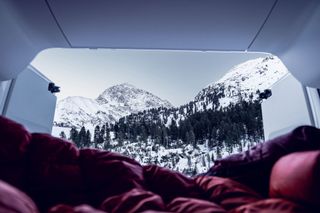 Mit Schlafsack im Camper vor Winterlandschaft