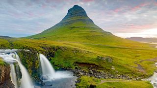 Ein Must-see auf der Island Rundreise ist der Kirkjufell, der bekannteste Berg Islands, grün bewachsen neben einem Wasserfall