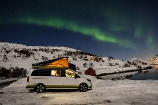 Ein Camper vor Polarlichtern in Norwegen.