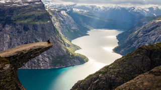 Person sitzt am Vorsprung der Trolltunga Norwegen