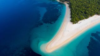 Ein Muss auf Deinem Urlaub in Kroatien mit Auto am Meer: der Strand Zlatni Rat mit weißem Sand, der sichelförmig ins türkisblaue Meer ragt aus der Luft fotografiert