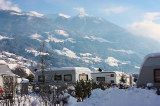Der Campingplatz Natürlich Hell im Winter. Man sieht die Berge im Hintergrund und einige Wohnmobile auf dem Platz.