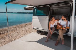 Couple sitting in a camper van playing guitare 