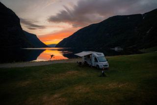 Camper at a mountain lake during a colorful sunset in Norway