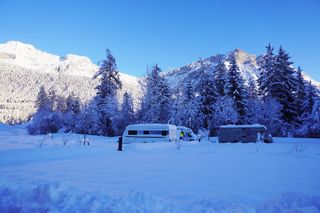 Mehrere Camper im Schnee umgeben von Bergen