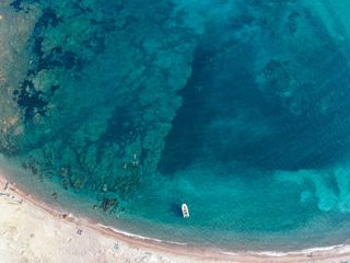 Im Meer vor dem Plage de Saleccia schwimmt ein Boot, im Wasser schwimmen ein paar Menschen und einige liegen am Strand. Für Karibik in Europa ist auch Korsika eine gute Wahl.