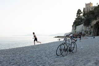 Eine Frau in Fahrradkleidung läuft Richtung Meer, am Strand stehen am Strand.