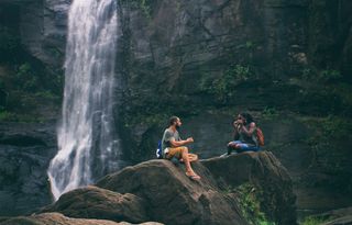 Zwei Freunde sitzen vor einem Wasserfall.
