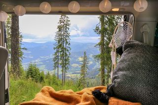 Blick aus dem Bett eines Campers auf ein Tal.