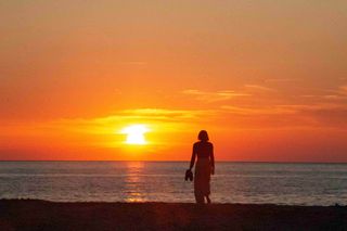 Person at sunset by the sea while camping in Corsica