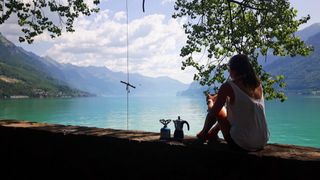 Frau sitzt mit Kaffee am See