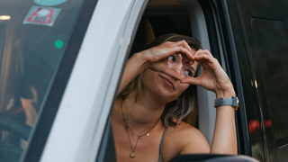Love is love: Eine junge Frau formt mit ihren Händen, die sie aus dem Fenster ihres Campers streckt, ein Herz