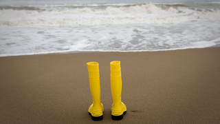 Gelbe Gummistiefel am Strand