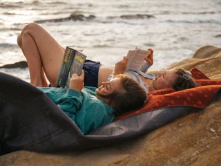 Zwei Frauen lesend an steiniger Küste