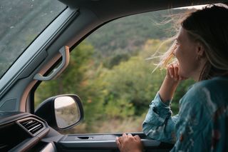 Frau sitzt in einem Off Camper und schaut aus dem Fenster