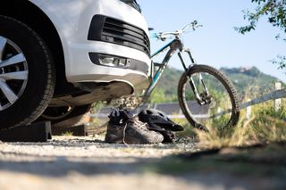 Vor einem weißen Off Camper liegen beim Camping in den Dolomiten Wanderschuhe und ein Helm, im Hintergrund steht in Fahrrad 