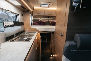 Kitchenette in the rear of the motorhome from Knaus: two-burner gas stove, storage space and sleeping area.