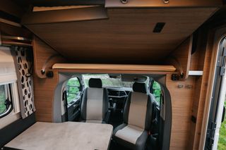 Front area in camper tourer van: roof bed, table and front seats