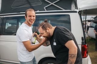 Lukas (Team Lead Stations) und Tim (Process Manager) stehen lachend vor einem CamperBoys Camper.