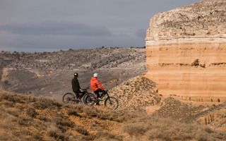 Zwei Mountainbiker auf ihren Rädern vor den Bergen.