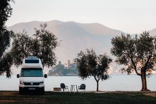 VW Grand California in front of mountain view with lake