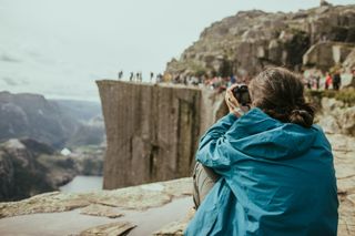 Eine Fotografin macht Bilder von einer Menschengruppe auf dem Preikestolen.