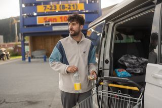 Ein Mann steht mit Einkaufswagen vor dem geöffneten Camper