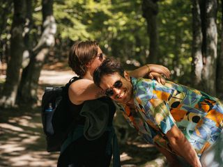Zwei Freunde im Sommer beim Camping Korsika. Sie lachen und eine Person trägt einen Rucksack.