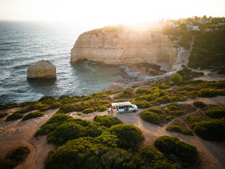 Eine Drohnenaufnahme von einem VW California Beach Van, der beim Überwintern in Portugal an der Küste steht.