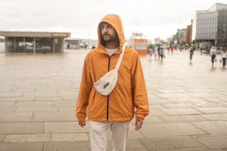 Urlaub Ostern: Ein Mann in oranger Regenjacke steht im April auf einem Platz in einer Stadt in den Niederlanden
