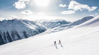 Zwei Wanderer die durch schneebedecktes Gebirge wandern