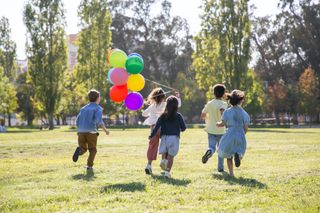 Children running on meadow with balloons