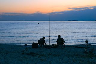 Das Meer vor Korsika beim Camping Korsika. Zwei Männer sitzen am Strand und Fischen.