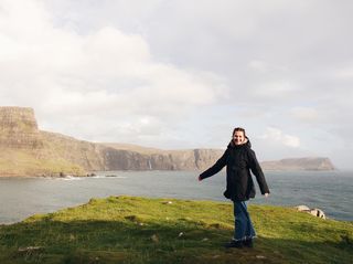 Male vom Off Guide steht an der Küste, dreht sich Richtung Kamera und lacht.