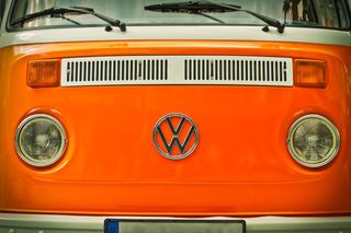 Organgener VW Bulli Campervan von vorne mit altem VW Logo